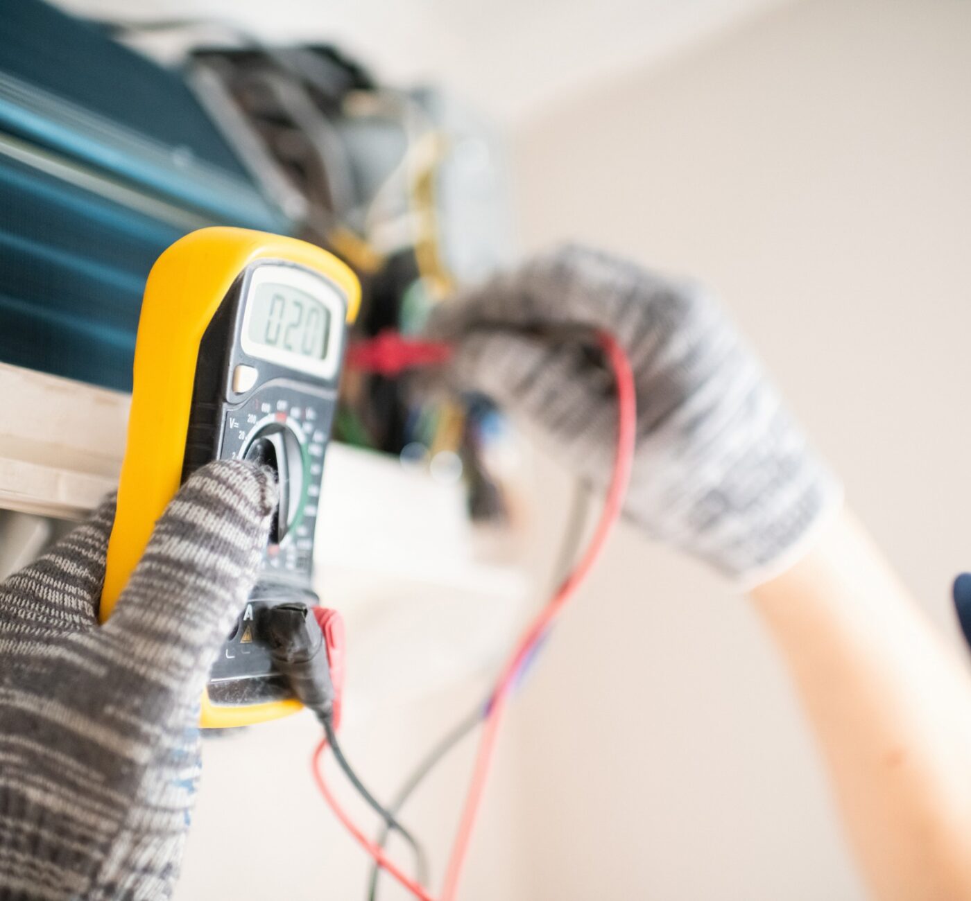 Technician with multimeter repairing air conditioner at home air conditioning servicing and maintenance in dunmow