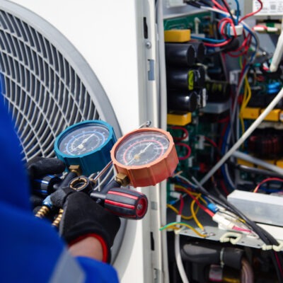 Air conditioner service .The air conditioner technician is using a gauge to measure the refrigerant pressure. air compressor. commercial heating maintenance stevenage